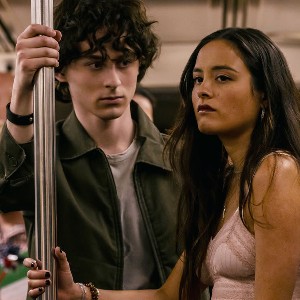 A white teen guy with curly brown hair standing in a subway car with a pretty, half Asian half white young woman with long dark hair