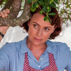 A pretty, middle-aged white woman with bob-length brown hair stands by a tree