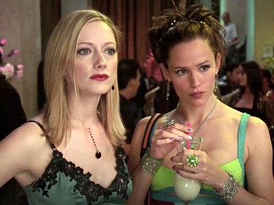 Judy Greer, a pretty blonde white woman with stern facial expression, and Jennifer Garner, a pretty white woman with brown hair holding a frozen cocktail. Both women are dressed in cocktail attire.