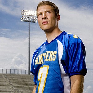 Matt Saracen, a white teenage boy with short brown hair and a sweet face, wearing a blue football jersey