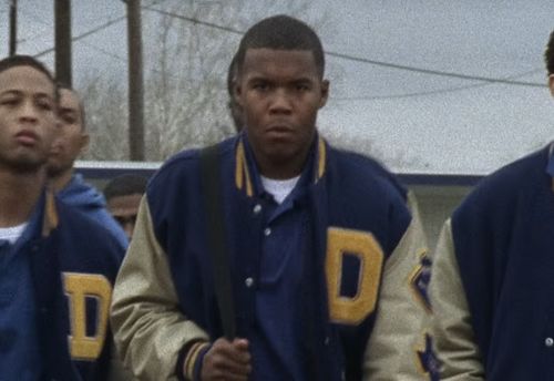 Smash Williams and a few other Black football players walking in a line in their letter jackets.