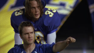 Tim Riggins pushes Jason Street out onto Panther field. The banner billows behind them and Jason raises a fist, looking tearfully off-camera