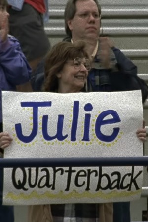 Grandma Saracen in the bleachers proudly holding a poster board sign that says 