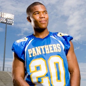 Smash Williams, a young handsome Black man wearing a blue Panthers jersey and grinning confidently