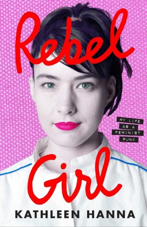 Cover of Rebel Girl, with a photo of Kathleen Hanna, a white woman with dark hair up in a ponytail and a slight smile with pink lips