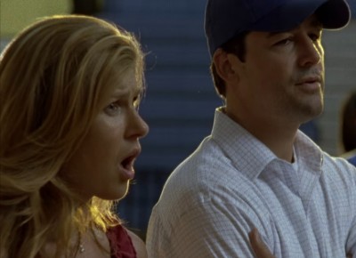 A white blonde woman with her jaw dropped in surprise next to a guy looking nonplussed in a baseball cap