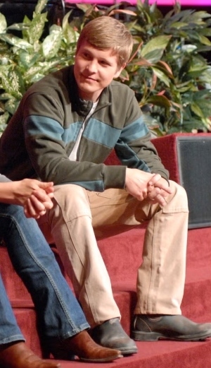 a blonde white man sits on carpeted stairs