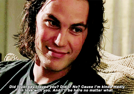 a young man with long brown hair smiles at a woman off camera while telling her that he loves her