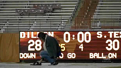 Taylor Kitsch as Tim Riggins in Friday Night Lights, kneeling on an empty football field, pair of cleats in hand