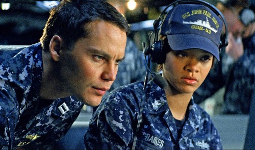 Taylor Kitsch and Rihanna, both wearing military camouflage uniforms and staring intently at a ship monitor